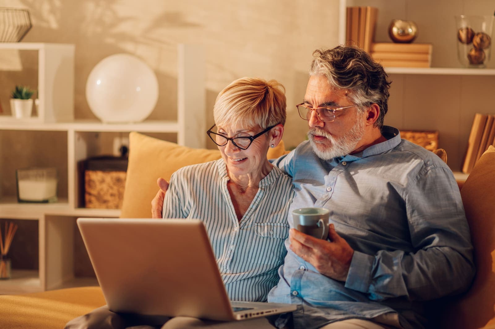 An older couple looking at a laptop together on their couch